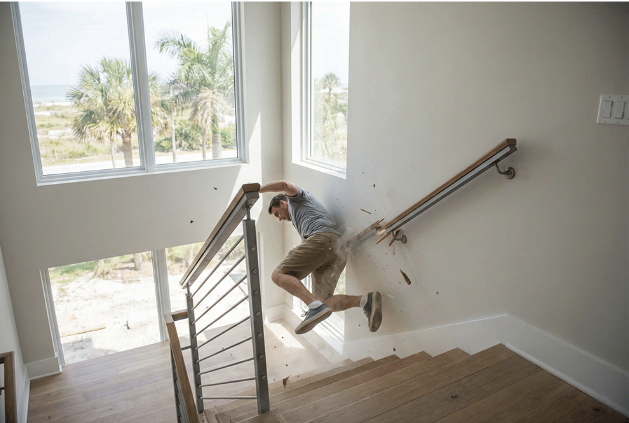 A man falling down a flight of stairs after the handrail broke.